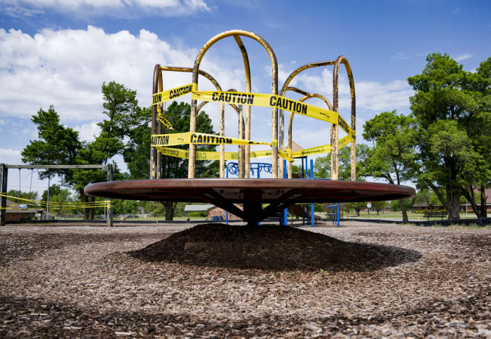 A playground spinner, roped off with caution tape.